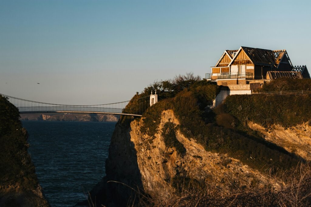 Scenic view of a house on a cliff with a bridge in Newquay, England during sunset.